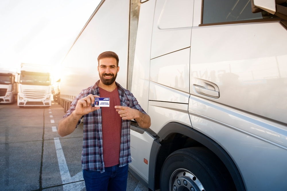 A man pointing with his left hand at his CDL holding in right hand