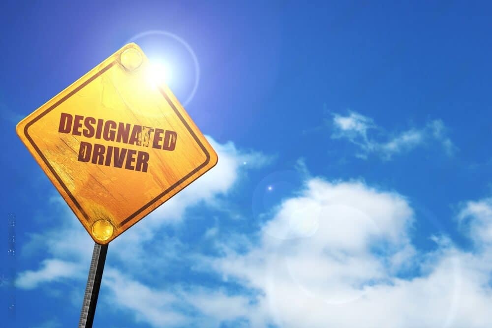 A yellow sign board written designated driver on it