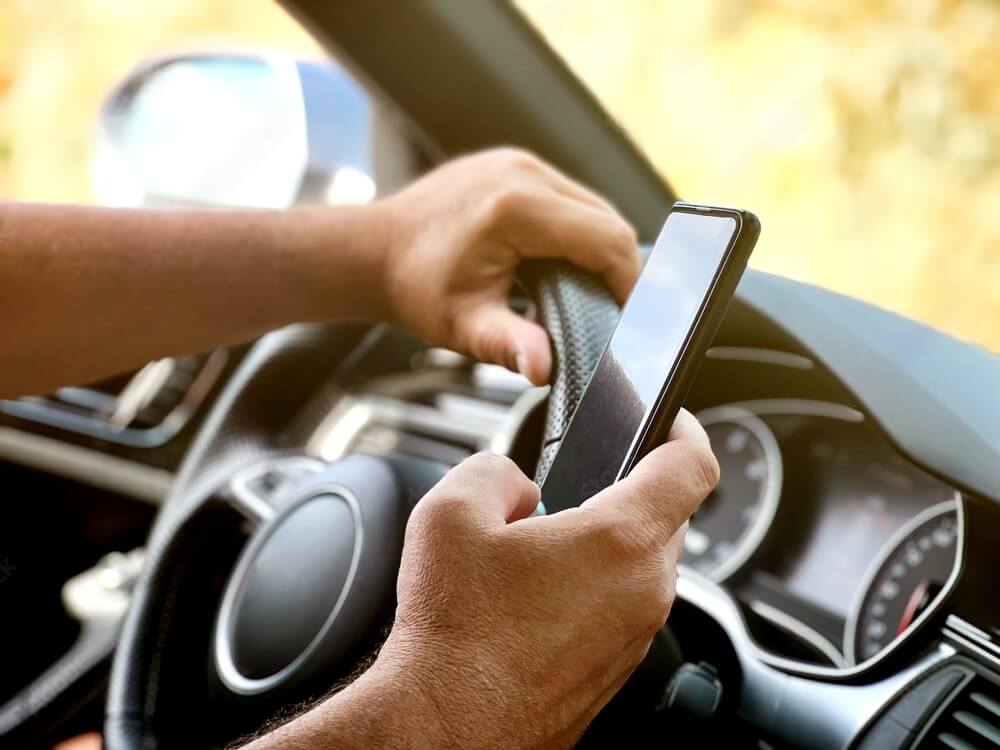 A man using buzzed driving apps while driving a car